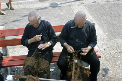 852322 Afbeelding van vissers tijdens het boeten van de netten in de haven van Spakenburg.